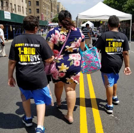 two boys wearing 1-800-HURT-911 T-shirts at Bronx street fair