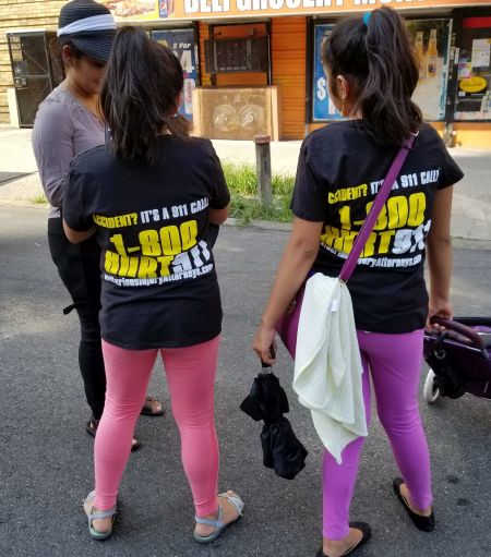 two girls wearing 1-800-HURT-911 T-shirts at Bronx street fair