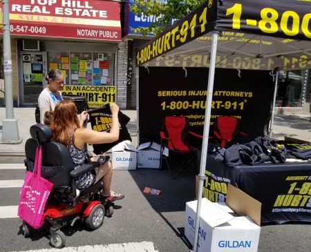 woman in a wheelchair at street fair looking at Bronx lawyer T-shirt