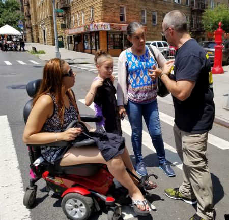 woman in a wheelchair talking to accident lawyer Rob Plevy at Bronx street fair