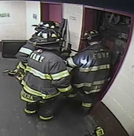 elevator doors being pried open by firefighters at an elevator accident