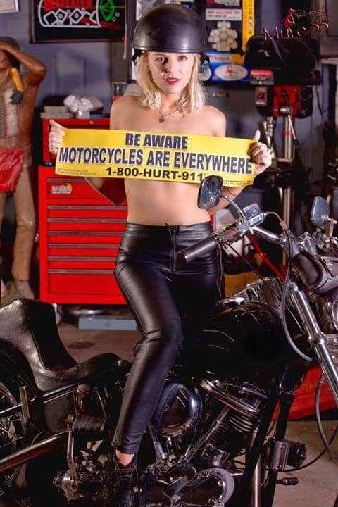 BE AWARE MOTORCYCLES ARE EVERYWHERE car sign held by woman not wearing a shirt